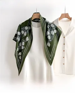Detail of dark green floral silk scarf showing white flower patterns and striped borders