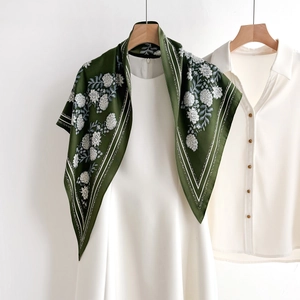 Dark green silk scarf with white floral patterns and border stripes on white dress