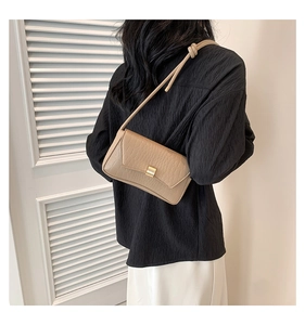 Dettaglio borsa in pelle beige goffrata coccodrillo con fibbia dorata