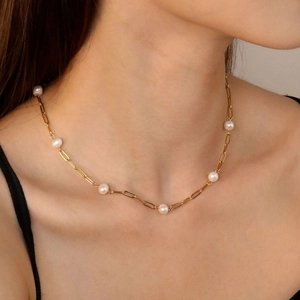 Détail d'un collier en perles d'eau douce sur une chaîne trombone dorée portée par un modèle