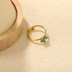 Detailed shot of gold adjustable ring with blue flower petals and textured background