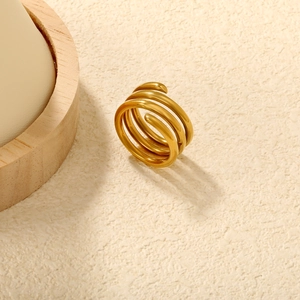 Detail of 18K gold plated multi-layer spiral ring on textured warm beige surface