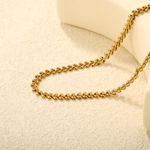18k gold plated stainless steel wheat link chain necklace on a minimalist ceramic base