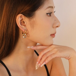 Minimalist two-tone oval hoop earrings in gold and silver finish worn by a model