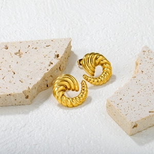 Detailed close-up of 18k gold plated croissant earrings on decorative stone texture