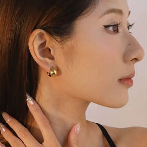 Close-up of model wearing polished gold water-drop hoop earrings with a minimalist design