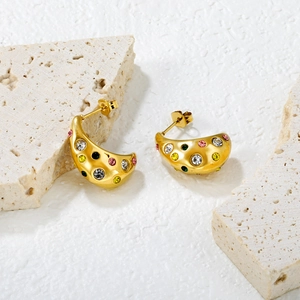 Detailed close-up of gold crescent earrings with vibrant colorful gemstones on a stone base