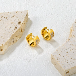 Close-up of gold hoop earrings with double-row cubic zirconia on stone background
