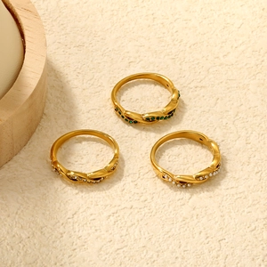 Detailed macro of gold twisted rings set with green gemstone and white pearls