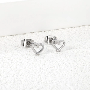 Détail macro de boucles d'oreilles cœur argentées ajourées avec fermoir sur pierre