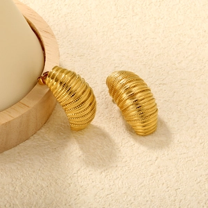 Détail de boucles d'oreilles croissant dorées avec texture nervurée et finition polie