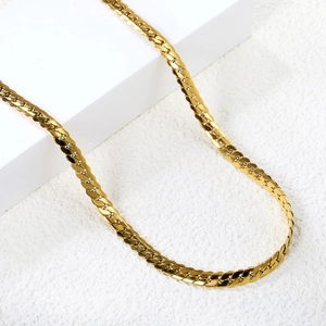 Flat Cuban link necklace in 18K gold-plated stainless steel on a white geometric display