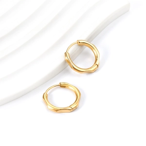 Détail de boucles d'oreilles créoles irrégulières en acier plaqué or 18 carats