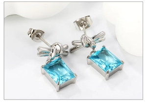 Macro shot of 18K silver-plated bow stud earrings with a rectangle blue zircon stone