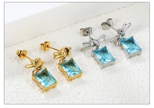 Detail view of gold and silver plated earrings with rectangular blue zircon drops