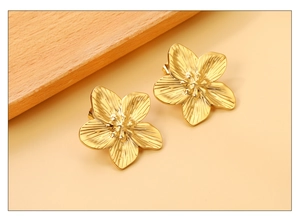 Macro detail of gold flower stud earrings showing fine radial texture and petals