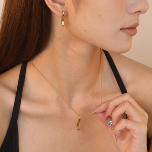 Minimalist gold teardrop pendant necklace and earrings set worn by a fashion model