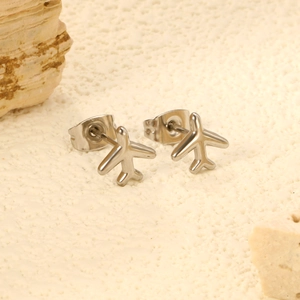Boucles d'oreilles avion minimalistes en argent poli sur une surface en pierre neutre