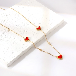 Elegant gold heart necklace with red shell charms and white zircon stones on stone plate