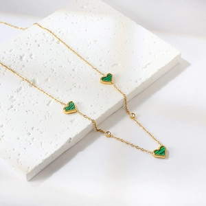 Detail of 18k gold heart necklace with green malachite heart pendants and zircons