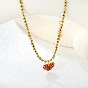 Golden beaded necklace featuring a sparkling heart pendant with pink crystals and lobster clasp