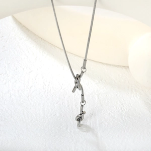 Macro detail of silver stainless steel snake chain with modern knot pendant design