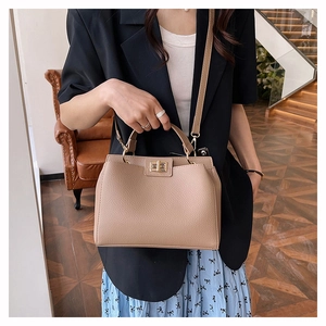 Détail du sac à main en cuir grainé beige avec fermoir doré porté par un mannequin