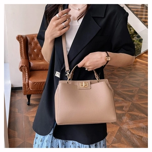 Détail du sac à main en cuir grainé beige avec fermoir rotatif doré et bandoulière