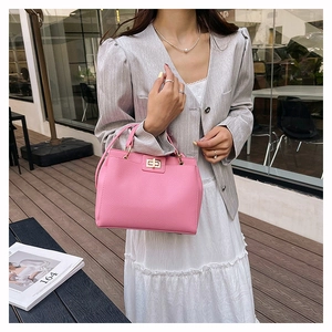 Détail du sac à main en cuir grainé rose vif avec fermoir rotatif en métal doré chic