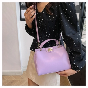 Gros plan d'un sac à main lilas en similicuir avec fermoir doré porté par un modèle