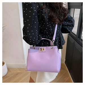 Détail du sac violet en similicuir avec fermoir rotatif doré et bandoulière réglable