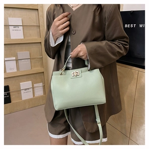 Détail d'un sac à main vert menthe texturé avec fermoir doré et bandoulière amovible