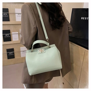 Gros plan d'un sac à main vert menthe avec fermoir doré porté par un mannequin en studio