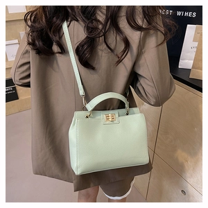 Détail du sac en cuir vert menthe avec fermoir rotatif doré porté par un mannequin