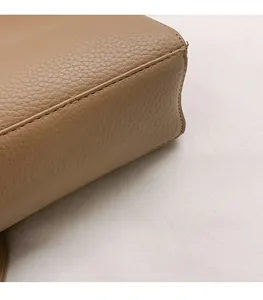 Gros plan de la texture cuir marron grainé avec coutures précises sur un sac à bandoulière