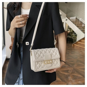 Borsa a tracolla beige trapuntata con chiusura a V dorata indossata da una modella