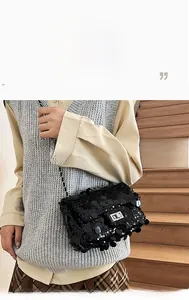 Detail of black sequined crossbody bag with silver twist lock and woven chain strap