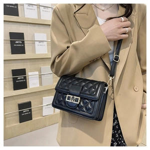 Borsa a tracolla trapuntata nera con chiusura a rotazione a V dorata su blazer kaki