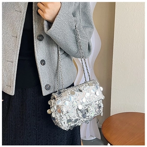 Detail of silver sequin square bag with chain strap worn with casual chic outfit
