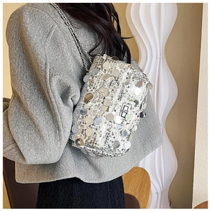 Silver sequin crossbody bag with chain strap styled on a grey wool coat for party outfits