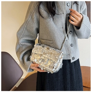 Silver sequin crossbody bag with chain strap and metallic lock shown on model outfit
