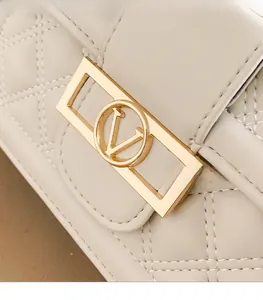 Dettaglio macro della borsa trapuntata beige con elegante fibbia in metallo dorato logo V