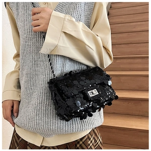 Fashionable black sequin crossbody bag with silver chain strap shown on a model