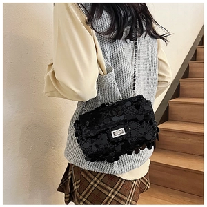 Detail of black sequin flap bag featuring a silver metal clasp and chain shoulder strap