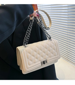 Detail of cream quilted crossbody bag with silver twist lock and chain strap