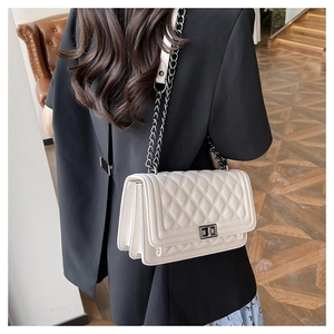 Detail of white quilted crossbody bag with metal chain strap and turn-lock closure