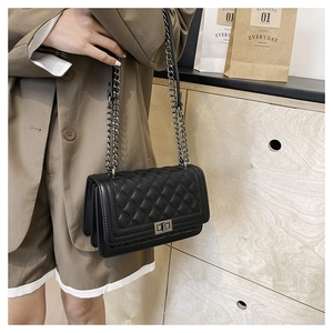 Detail of black quilted chain bag with silver clasp and side gusset structure on a model