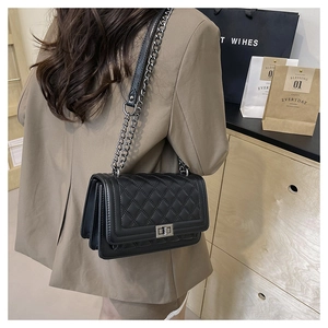 Detail of black quilted leather shoulder bag with vintage metal turn-lock and chain strap
