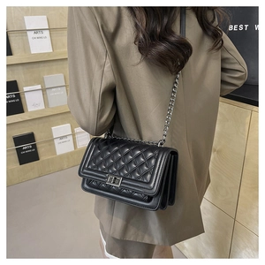 Detail of classic black quilted chain bag with gold metal twist lock and leather strap