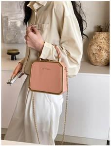 Detail of a pink octagonal box bag with gold trim, twisted handle and chain strap